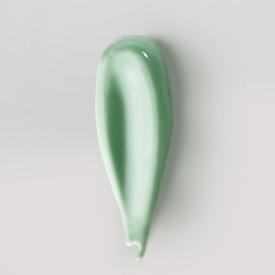 Traccia di crema verde su sfondo chiaro. La crema ha una consistenza liscia e una forma allungata.