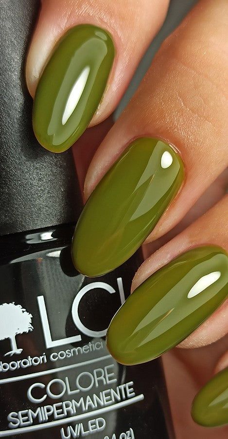 Primo piano di dita con smalto verde. Flacone parzialmente visibile. Scritta: LCI, Colore Semipermanente.