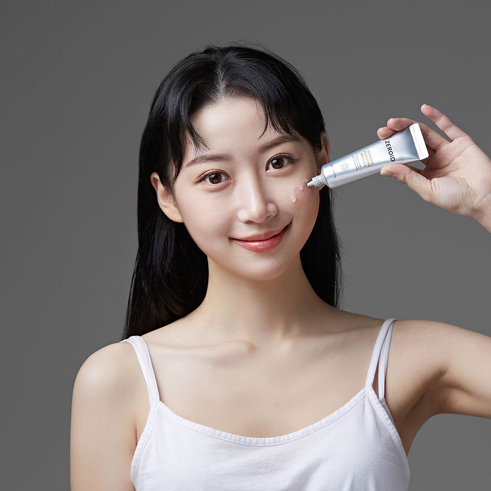 Donna tiene un tubo. Prodotto applicato sulla pelle. Tubo con "ZEROID" e "Intensive Hydrating Ampoule".