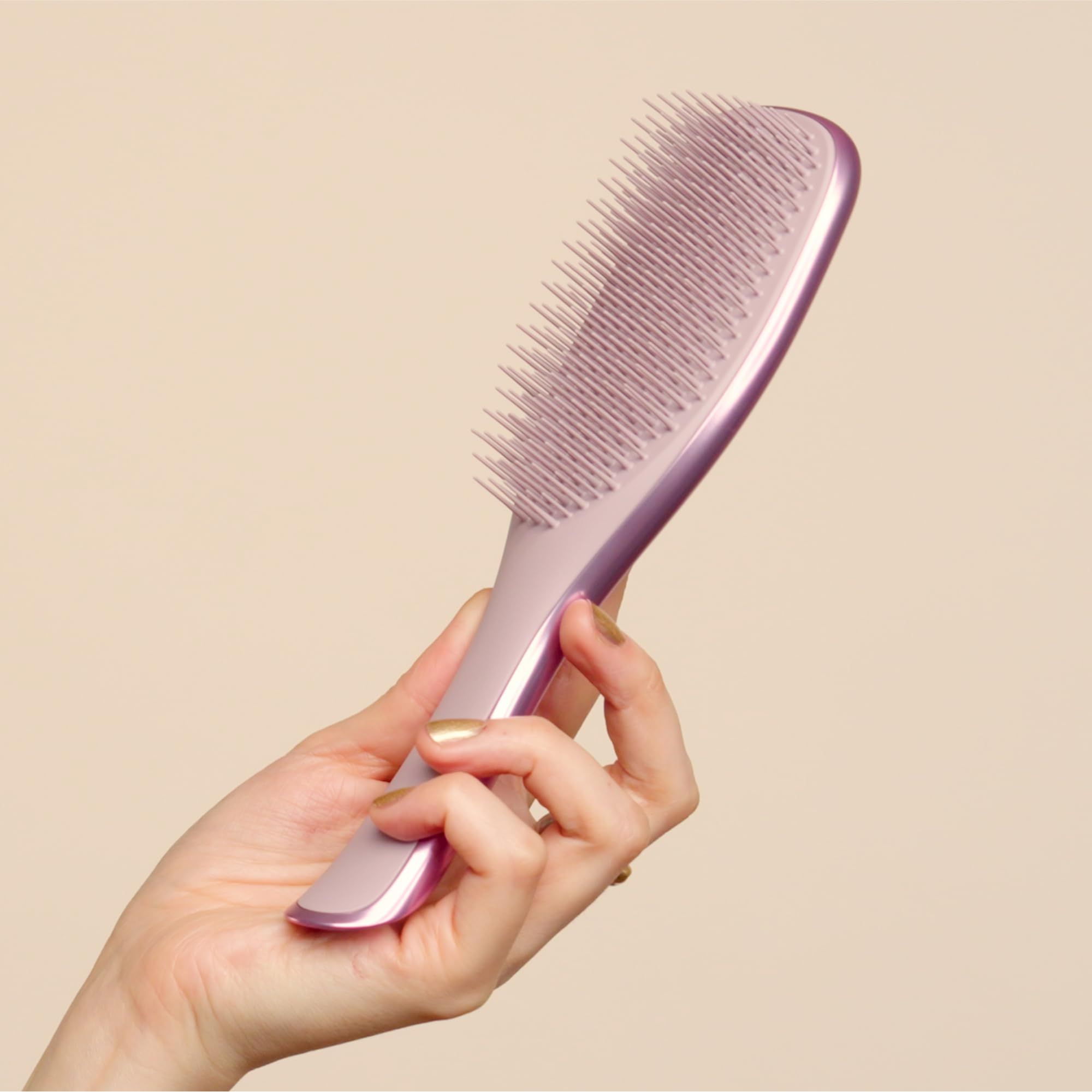 Spazzola rosa in una mano. L'impugnatura è ergonomica.