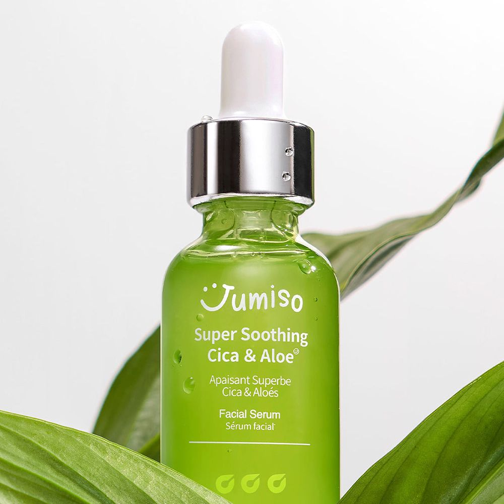 Flacone di vetro verde con tappo bianco e pipetta, circondato da foglie verdi. Scritta: Super Soothing Cica & Aloe.