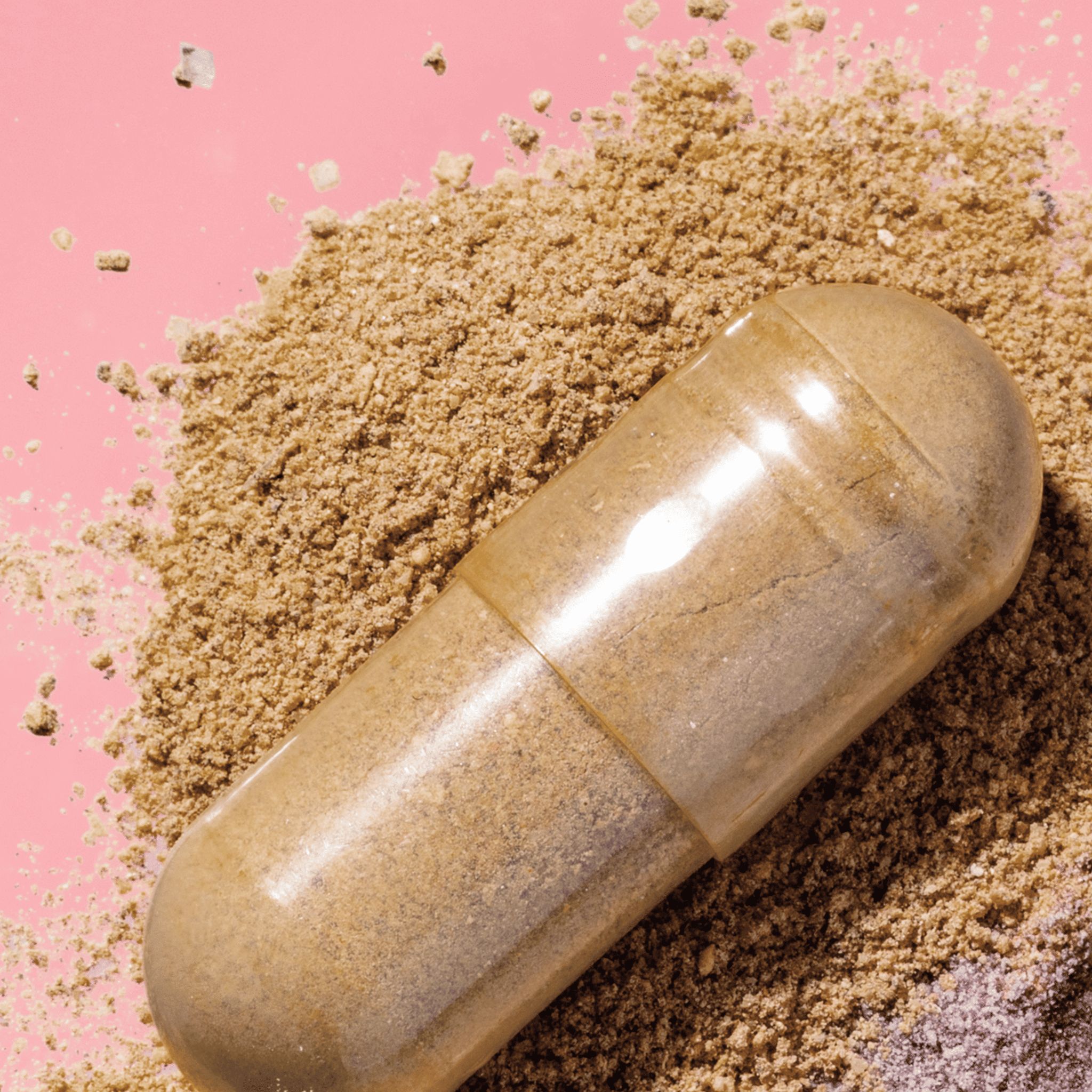 Primo piano di una capsula su polvere marrone. Capsula trasparente, in due parti.