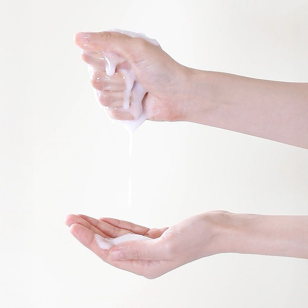 Mani che tengono una sostanza liquida bianca. Il liquido gocciola nella mano inferiore.