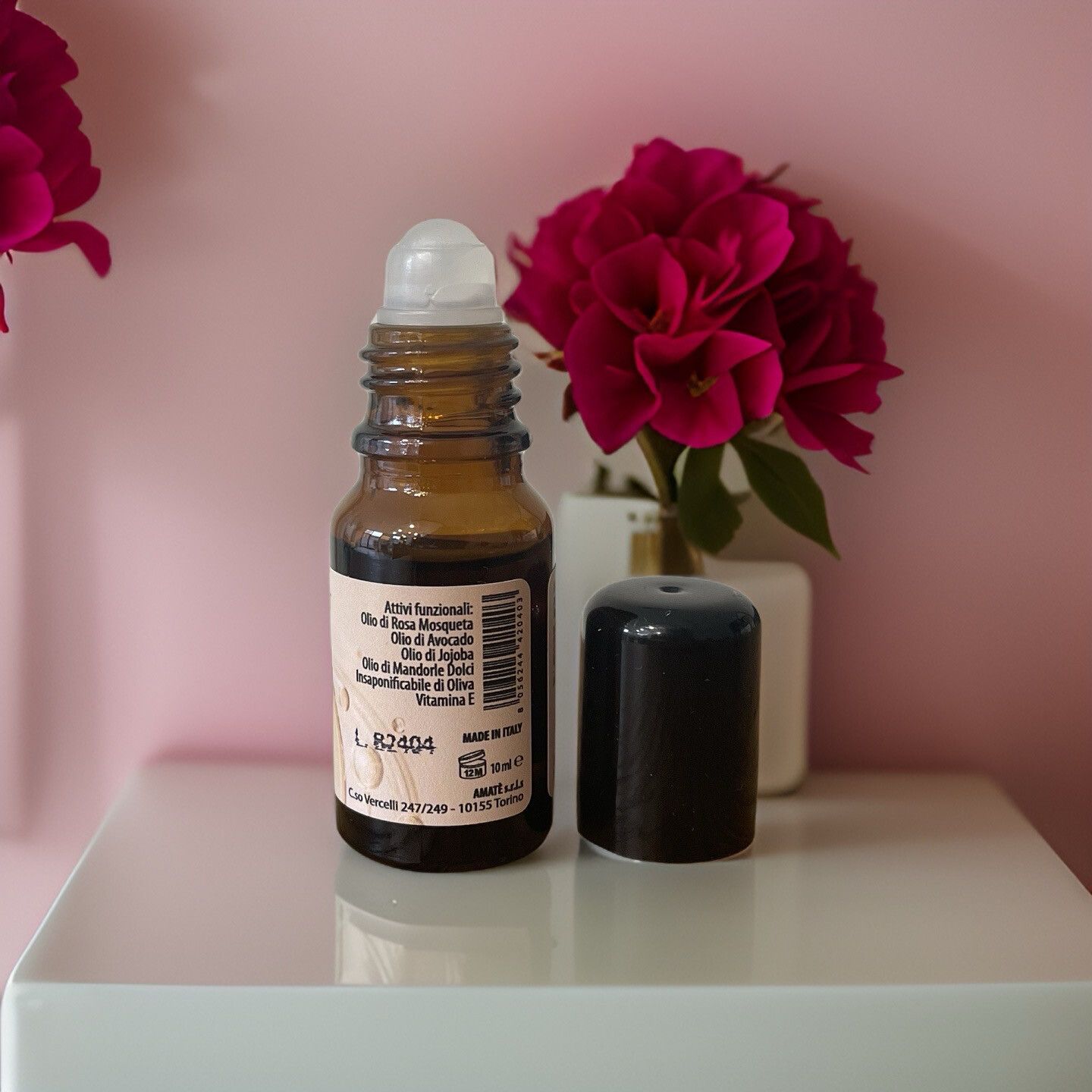 Flacone di vetro marrone con applicatore roll-on e tappo nero. Scritta. Marchio: AMATÈ.