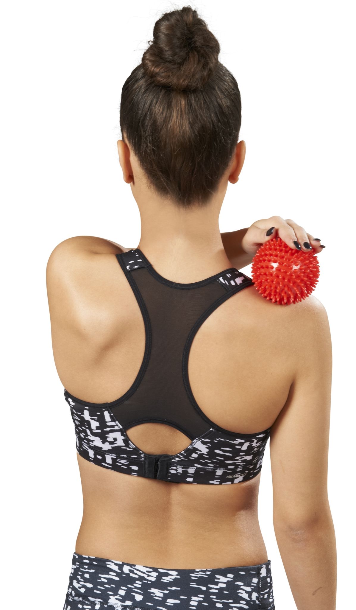 Donna tiene una sfera rossa appuntita sulla spalla. Indossa abbigliamento sportivo.