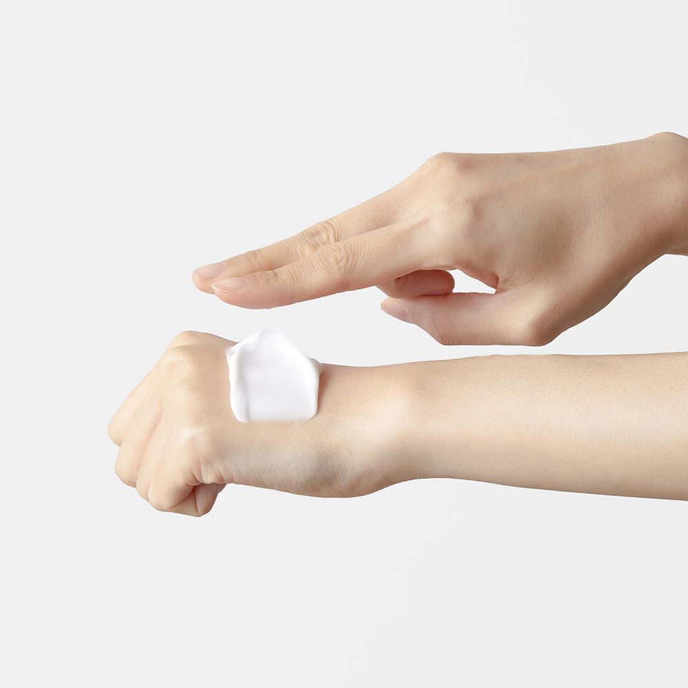 Mani con crema. Una mano applica la crema. Crema bianca sulla pelle.
