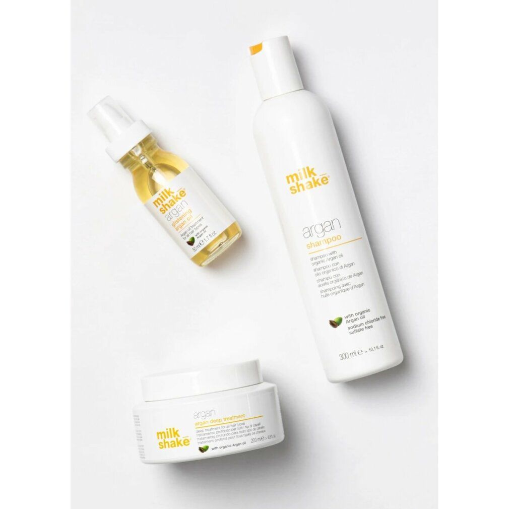 Tre prodotti: shampoo, olio e crema. Scritta: milk_shake argan. Con olio di argan. Design bianco.