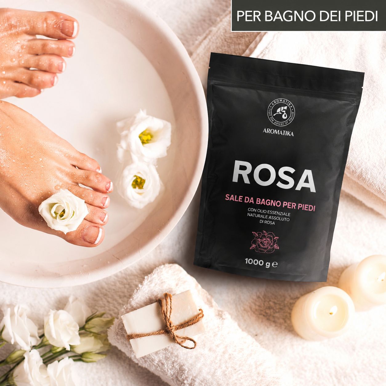Piedi in una ciotola con sali da bagno Rose. Sacchetto nero, logo Aromatica, 1000 g. Asciugamano, sapone, candele, fiori.