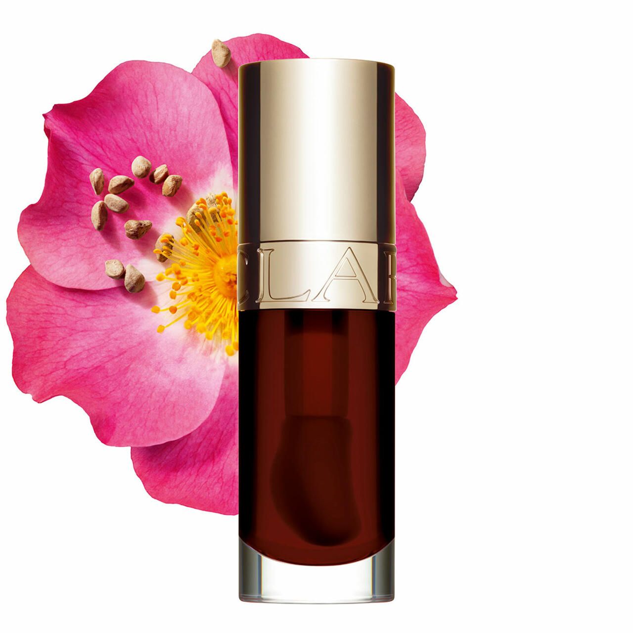 Clarins Lip Comfort Oil rosso scuro accanto a un fiore rosa.