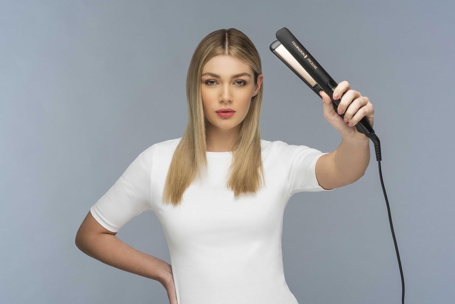 Donna bionda tiene una piastra nera. Guarda la fotocamera. La piastra è visibile.