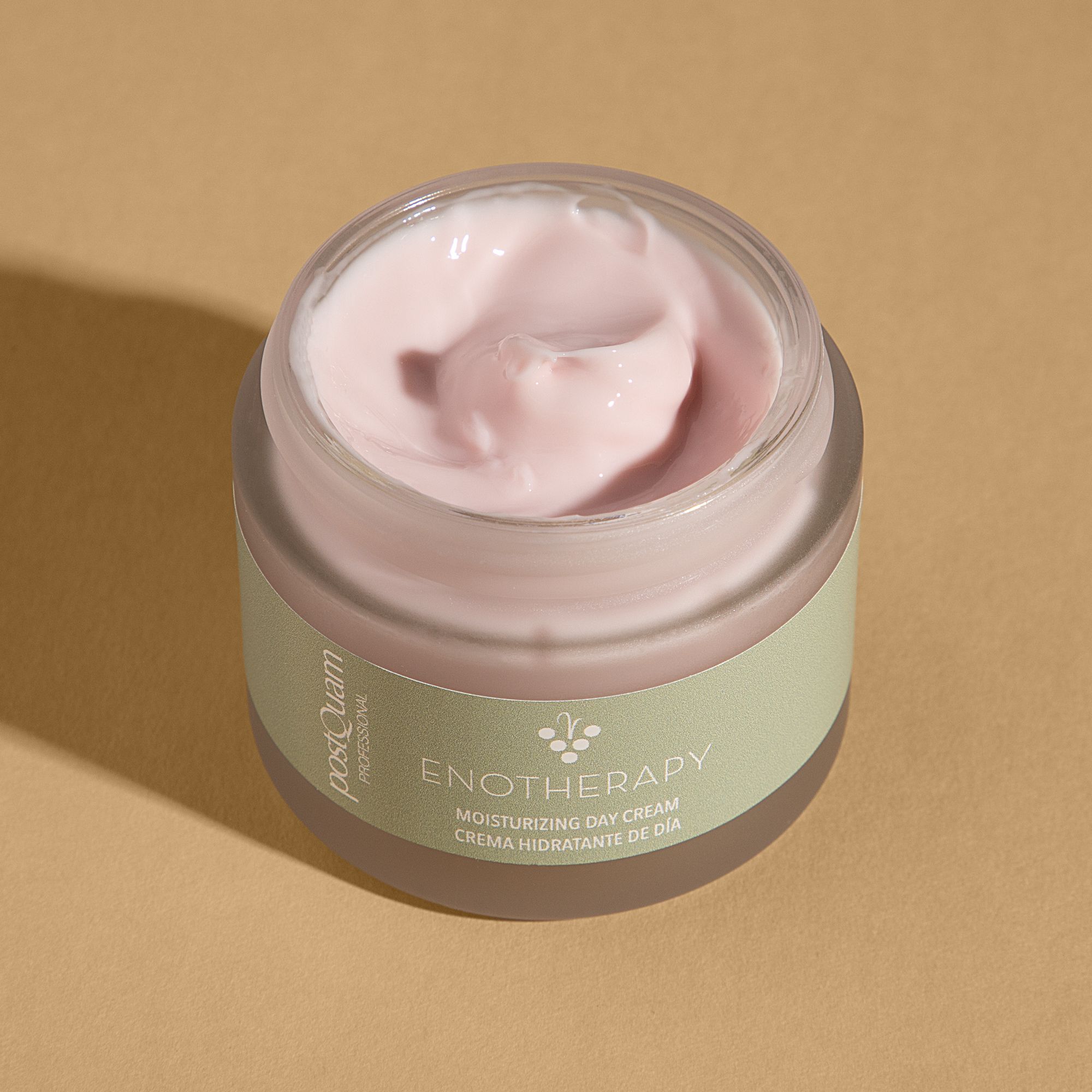 Vaso di crema aperto. Crema rosa visibile. Scritta: PostQuam, Enotherapy, Moisturizing Day Cream. Adesivo verde.