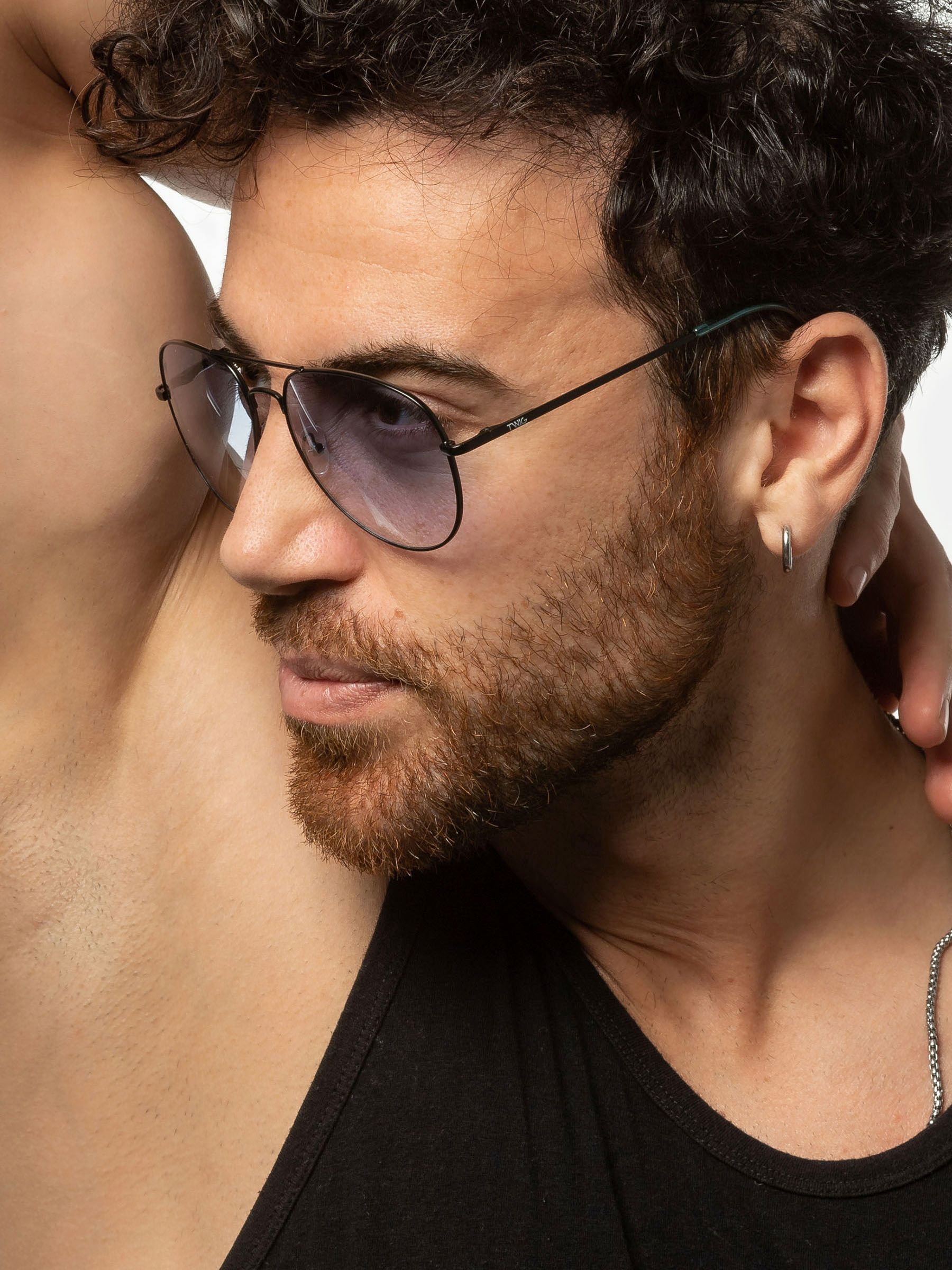 Uomo con occhiali da sole. Montatura nera, lenti blu. Primo piano.