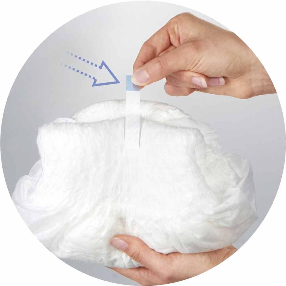 Primo piano di una persona che applica una striscia adesiva sui pantaloni per incontinenza. Le frecce indicano la direzione.