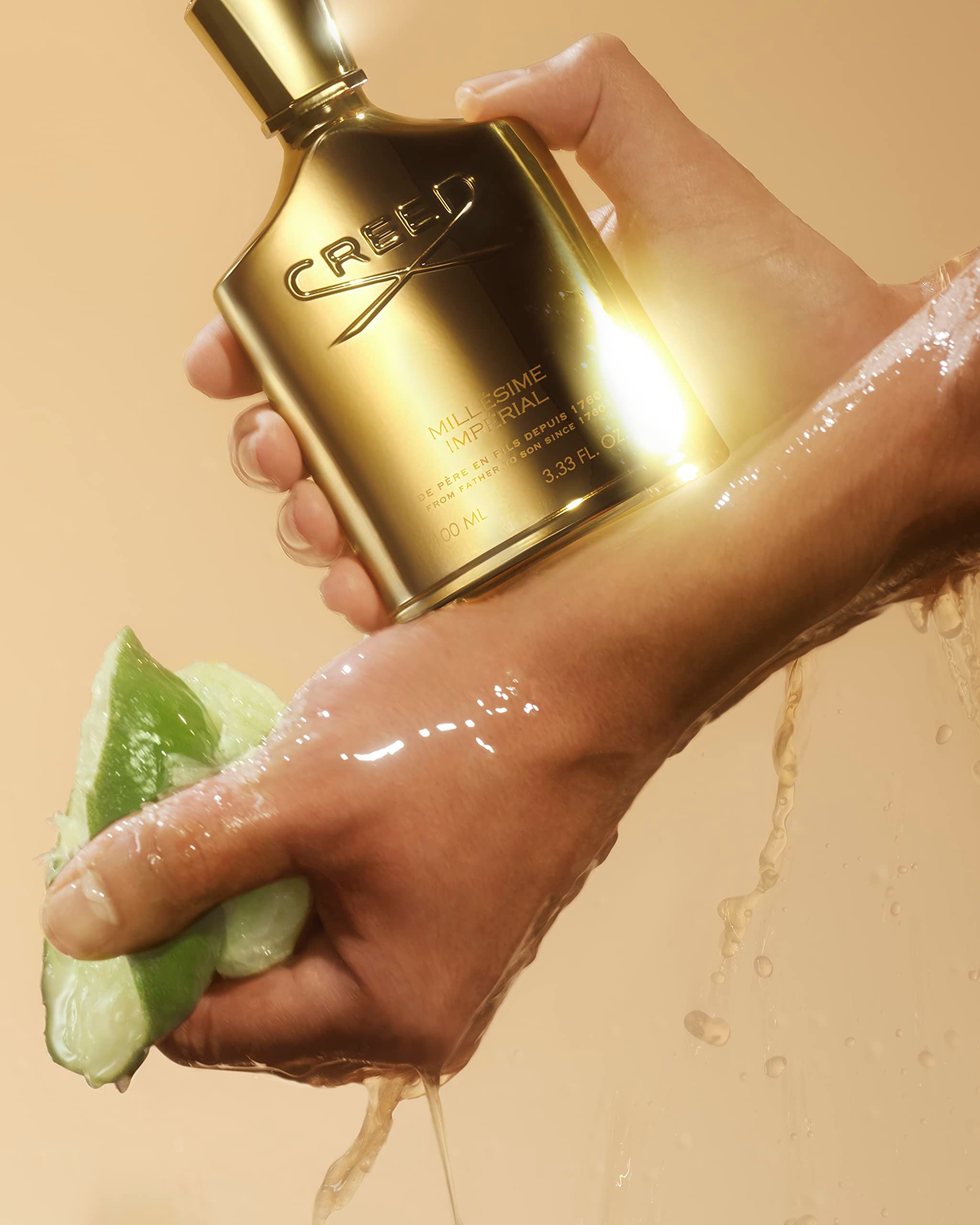 Flacone dorato in una mano, con succo di lime. Scritta CREED MILLÉSIME IMPERIAL.