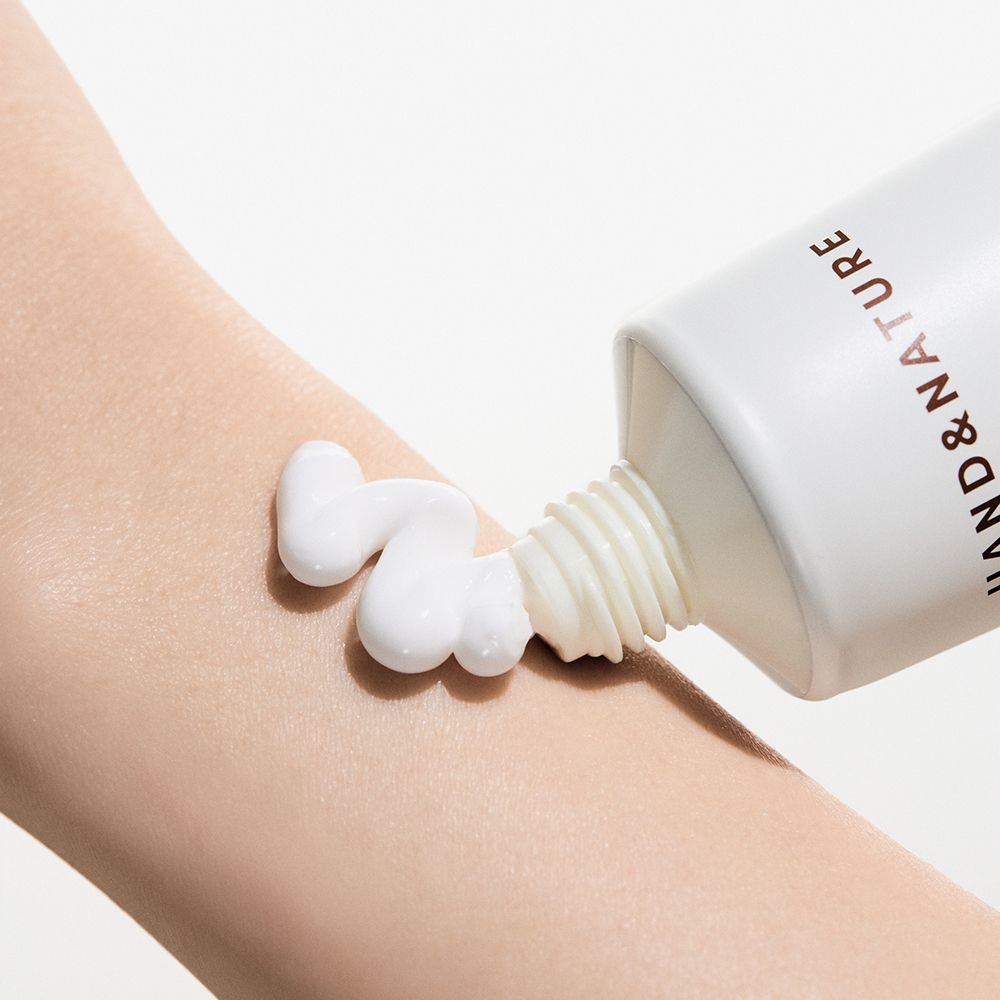 Crema mani applicata su una mano da un tubetto. La crema è bianca.