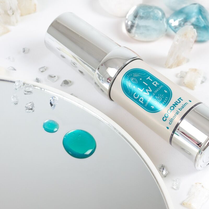Flacone cilindrico con testo CLIT PWR Coconut. Su uno specchio con gocce. Elementi decorativi.