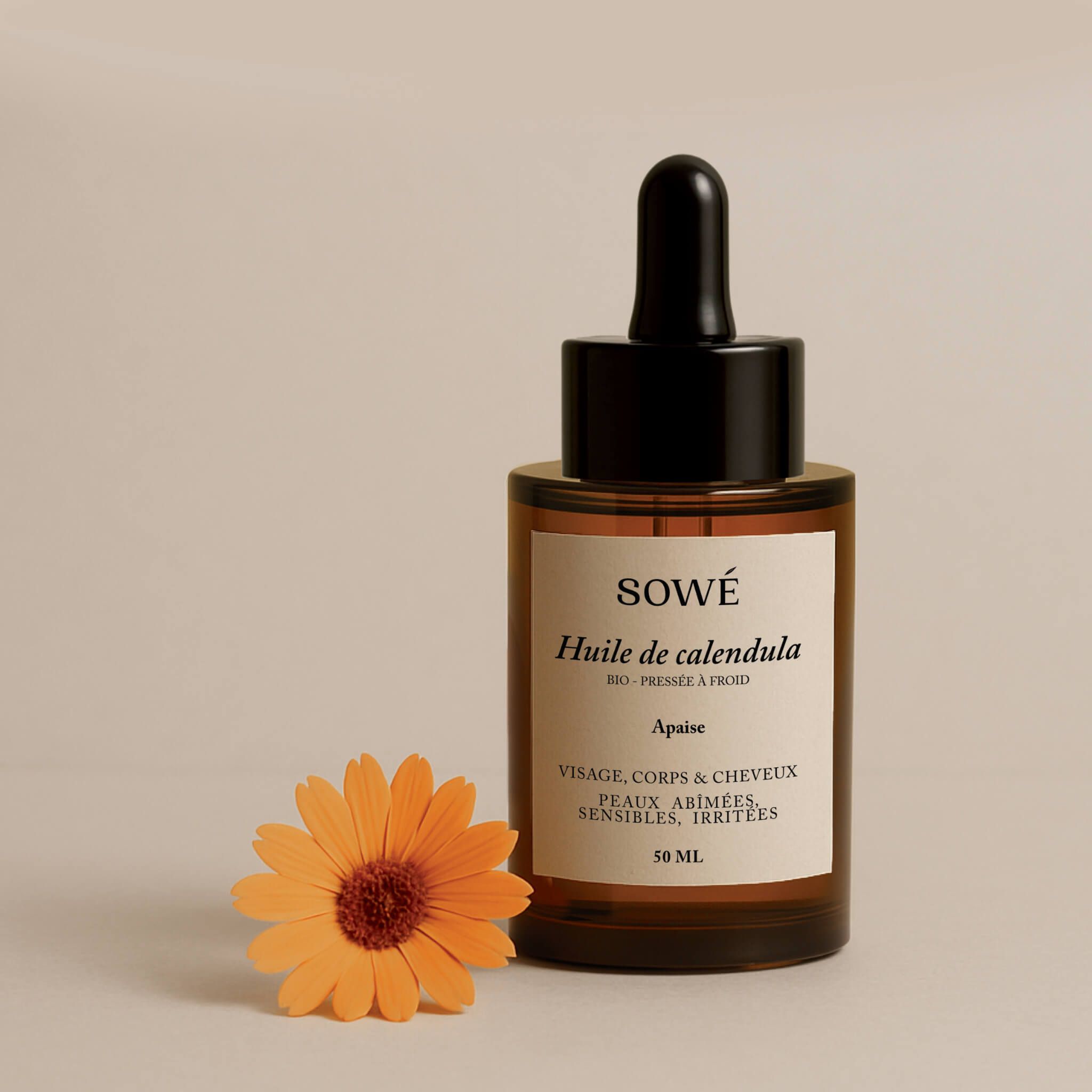 Flacone di vetro marrone con contagocce e liquido giallo. Etichetta con nome del prodotto. Calendula arancione accanto.