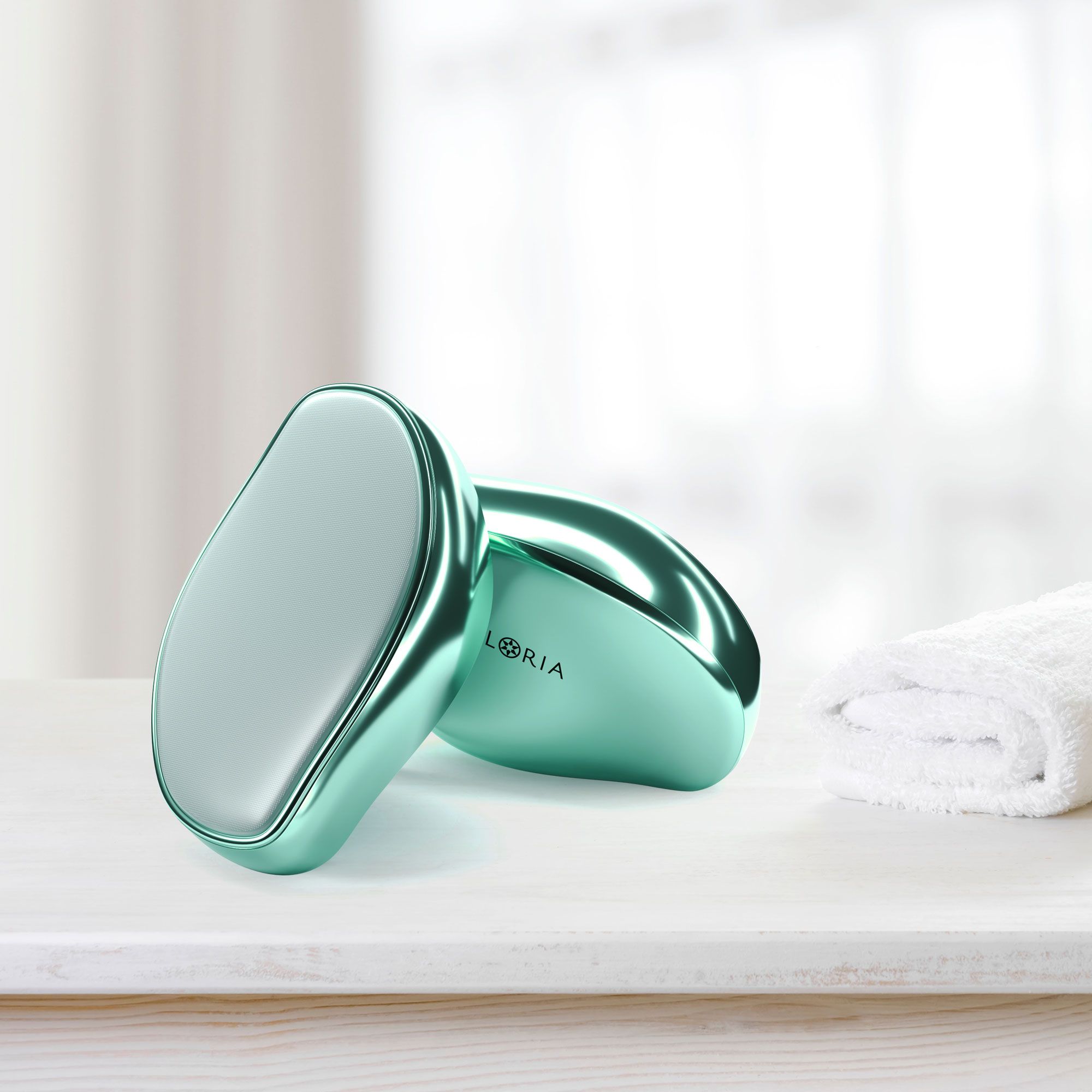 Due epilatori ovali verdi su una superficie bianca. Asciugamano sullo sfondo.