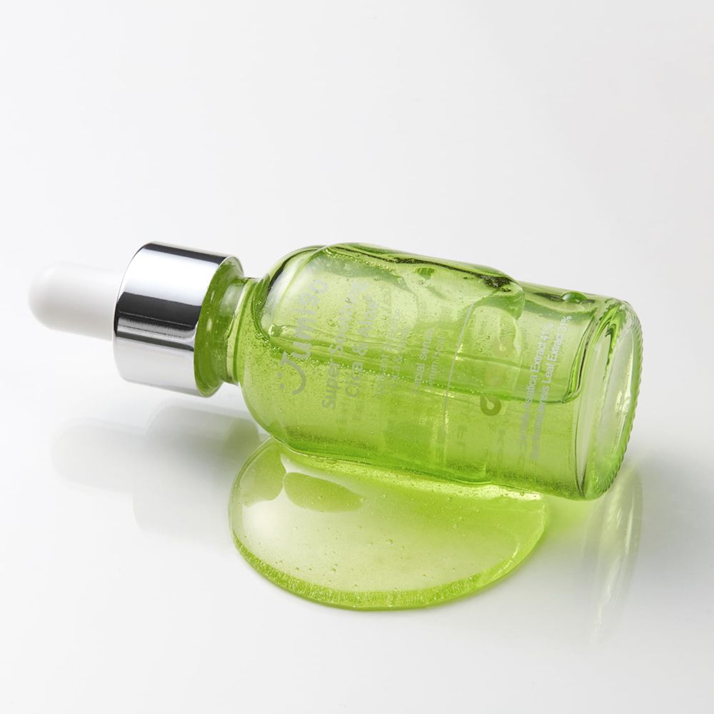 Flacone di vetro verde con tappo bianco e pipetta appoggiato su una superficie bianca. Accanto, una pozza di siero.
