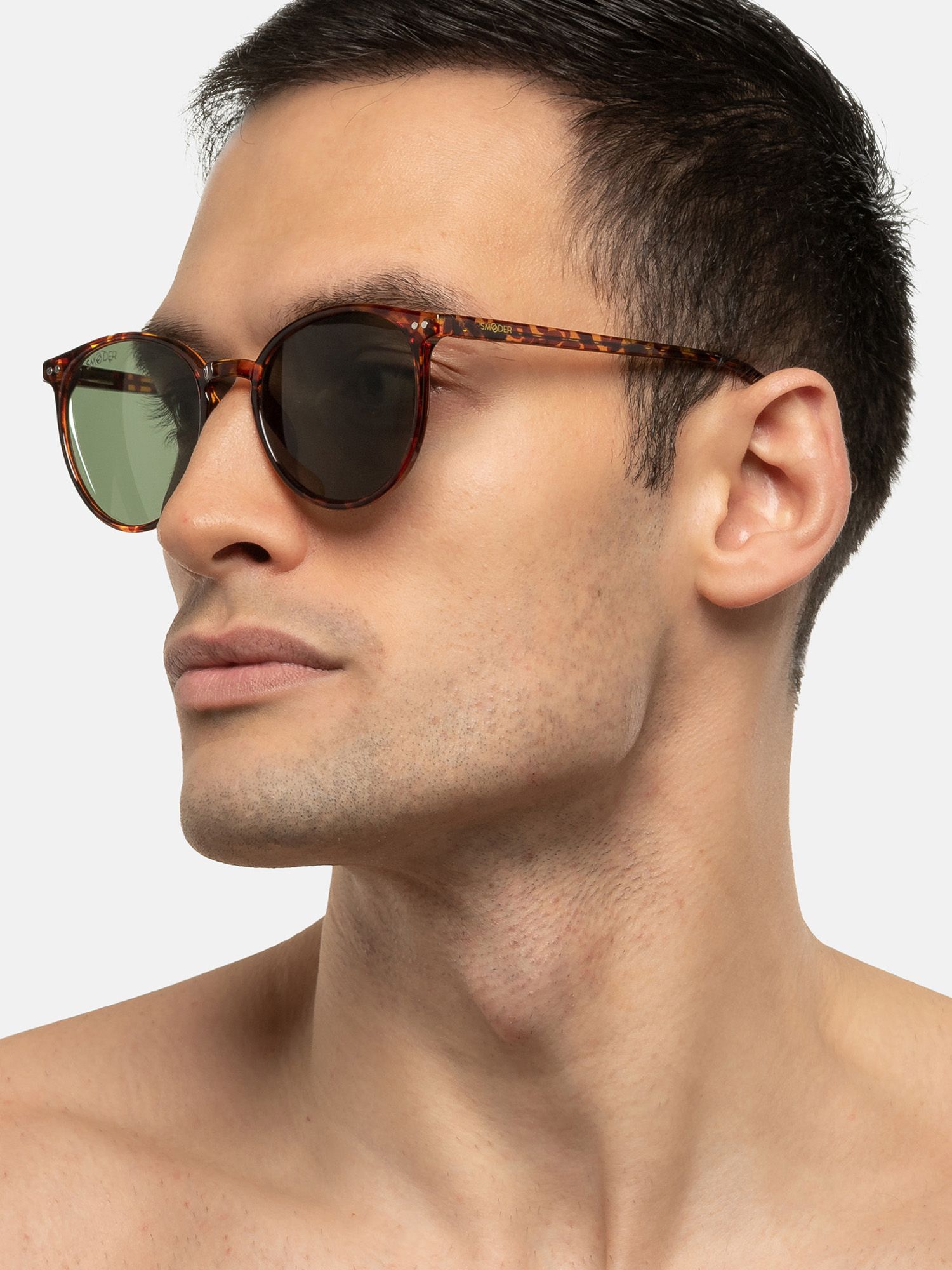 Uomo con occhiali da sole, motivo tartarugato marrone. Lenti verdi. Primo piano.