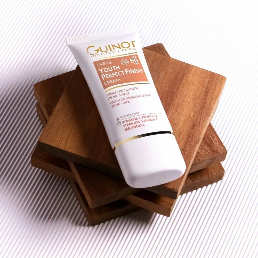 Tubo bianco con dettagli dorati, su blocchi di legno. Scritta: Crème Youth Perfect Finish Cream, SPF 50.