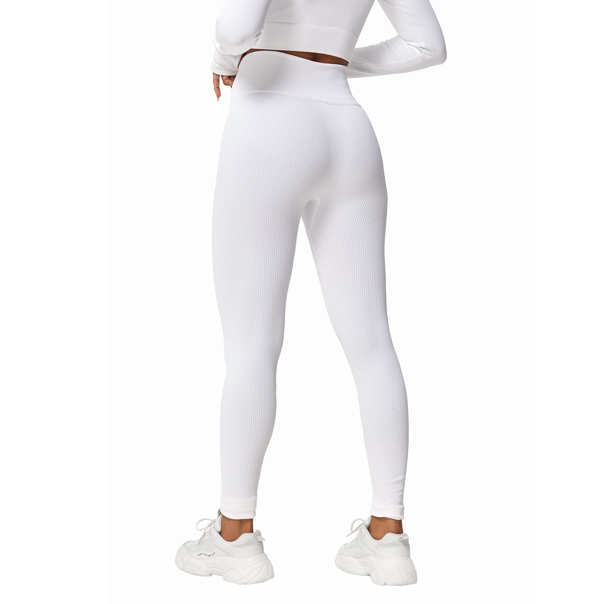 Leggings bianchi aderenti e top coordinato a maniche lunghe, indossati con scarpe da ginnastica bianche.
