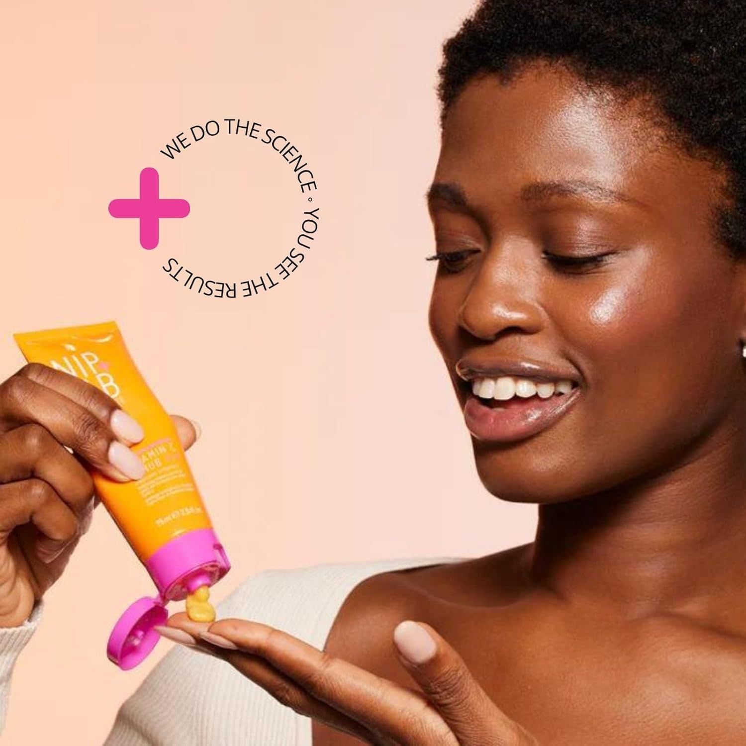 Donna tiene tubo prodotto. Tubo giallo-arancio, tappo rosa. Testo: Nip + Fab, Vitamina C.