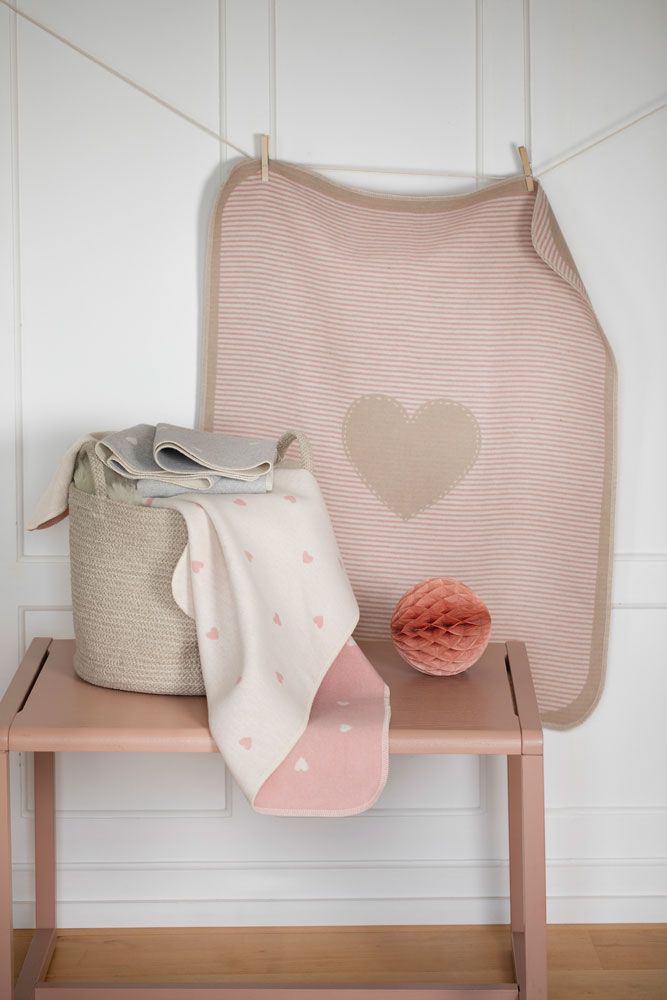 Coperta per neonati a righe con un cuore applicato, appesa a una scala.