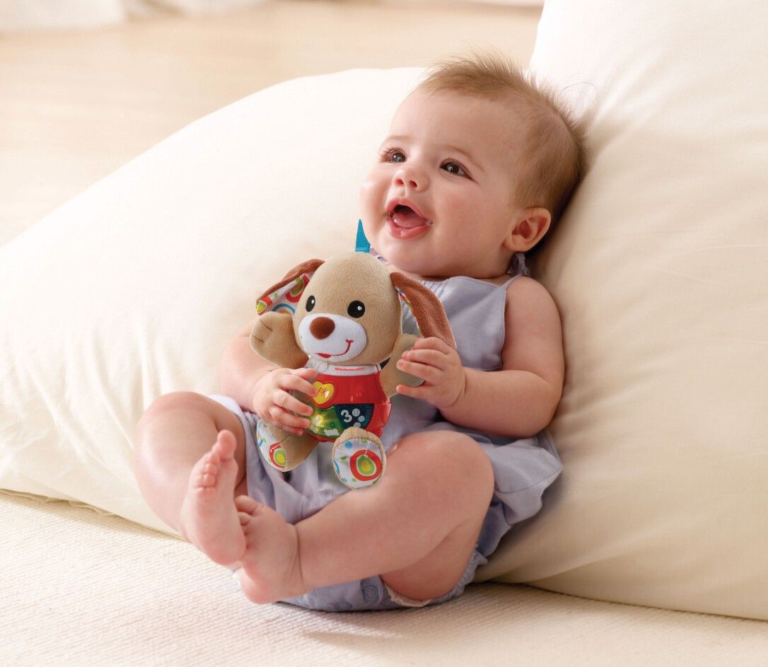 Bambino seduto che tiene in mano un cagnolino di peluche beige con un gilet rosso. Con numeri e luci.