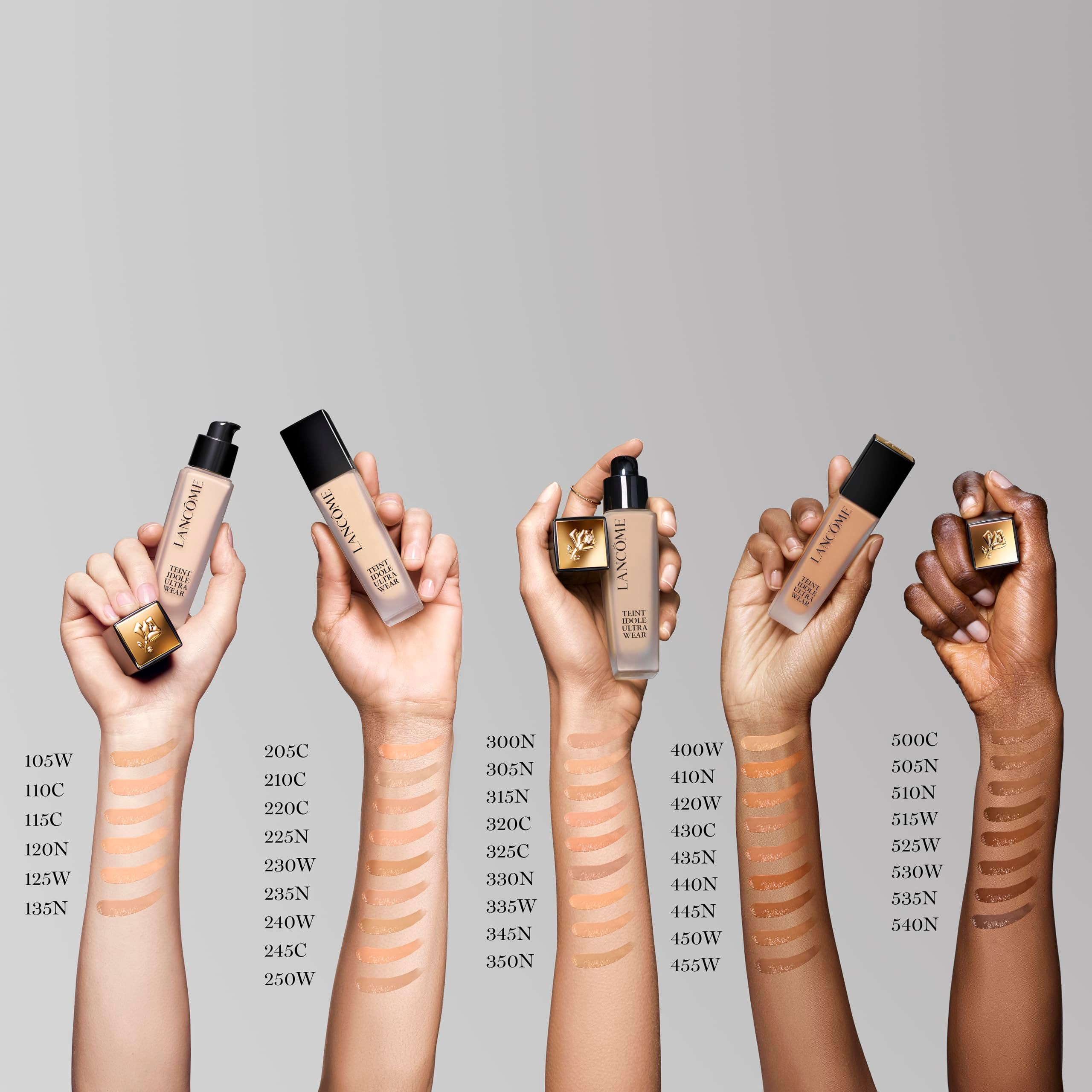 Mani che tengono diverse tonalità di Lancôme Teint Idole Ultra Wear. Numeri di tonalità e flaconi del prodotto.