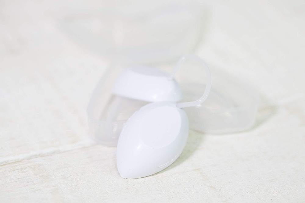 Prodotto bianco ovale in un involucro trasparente in due parti. Il prodotto è davanti all'involucro aperto.