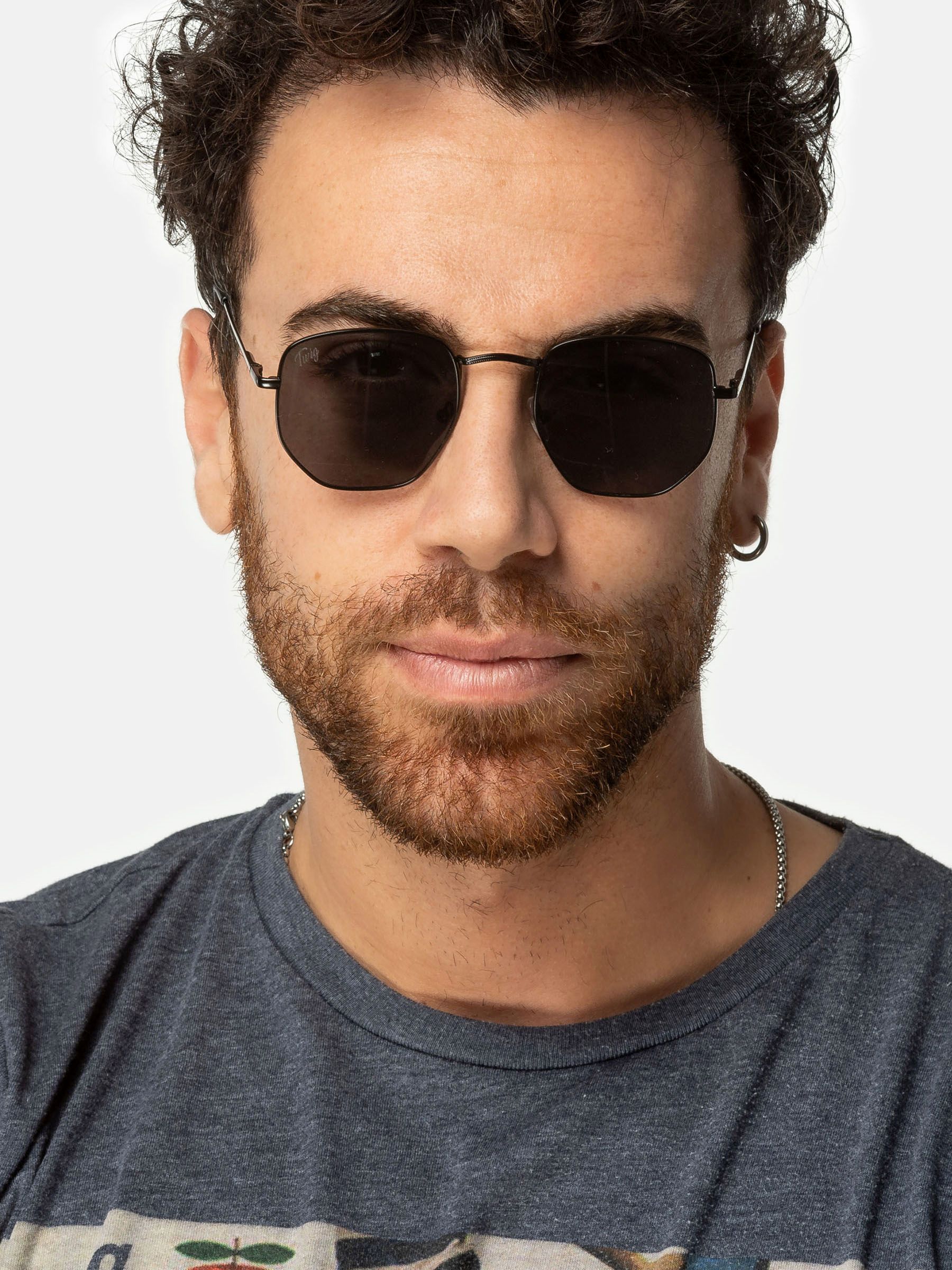 Uomo con occhiali da sole Twig, montatura nera, lenti esagonali.