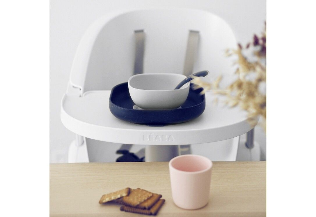 Set di stoviglie BEABA 4 pezzi. Piatto, ciotola, tazza e cucchiaio. Su seggiolone. Tazza rosa, biscotti.