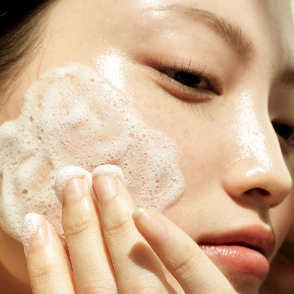 Persona con schiuma sul viso. La schiuma è bianca.