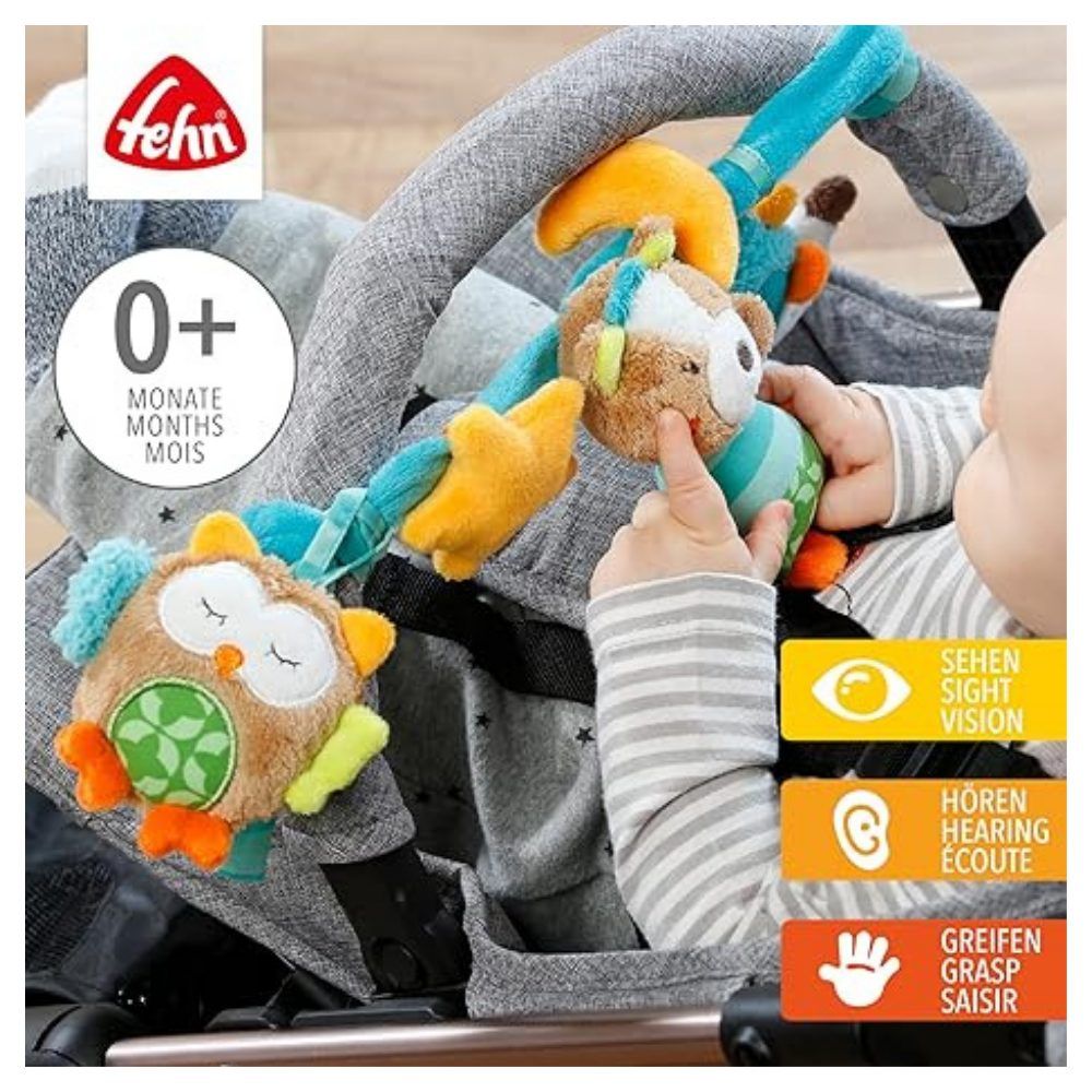 Catena per passeggino con peluche. Bambino tocca i giocattoli. Marchio 'fehn' e raccomandazione di età '0+ mesi' visibili.