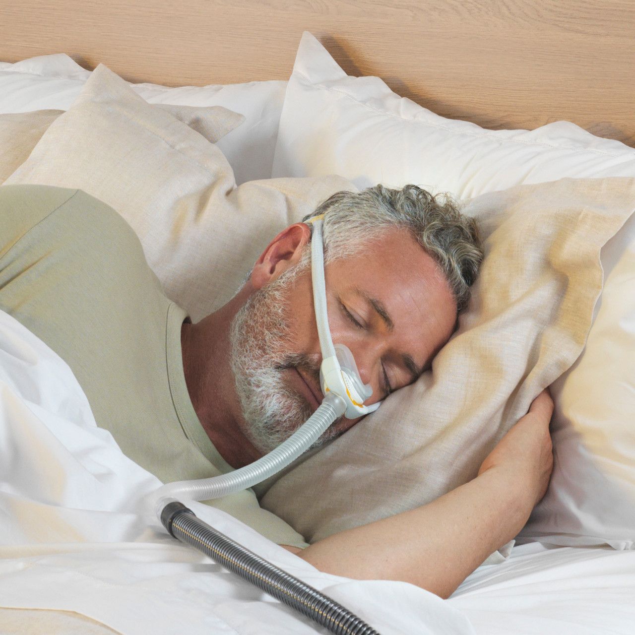 Uomo che dorme con una maschera nasale grigia e gialla e un tubo.