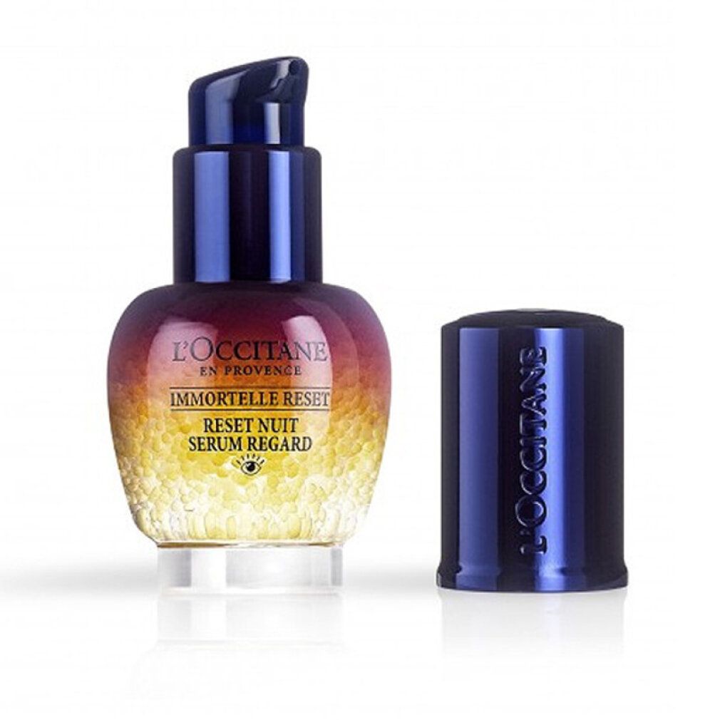 Flacone di siero con tappo blu rimosso. Scritte: L'Occitane, Immortelle Reset, Reset Nuit Serum Regard. Sferette gialle visibili.