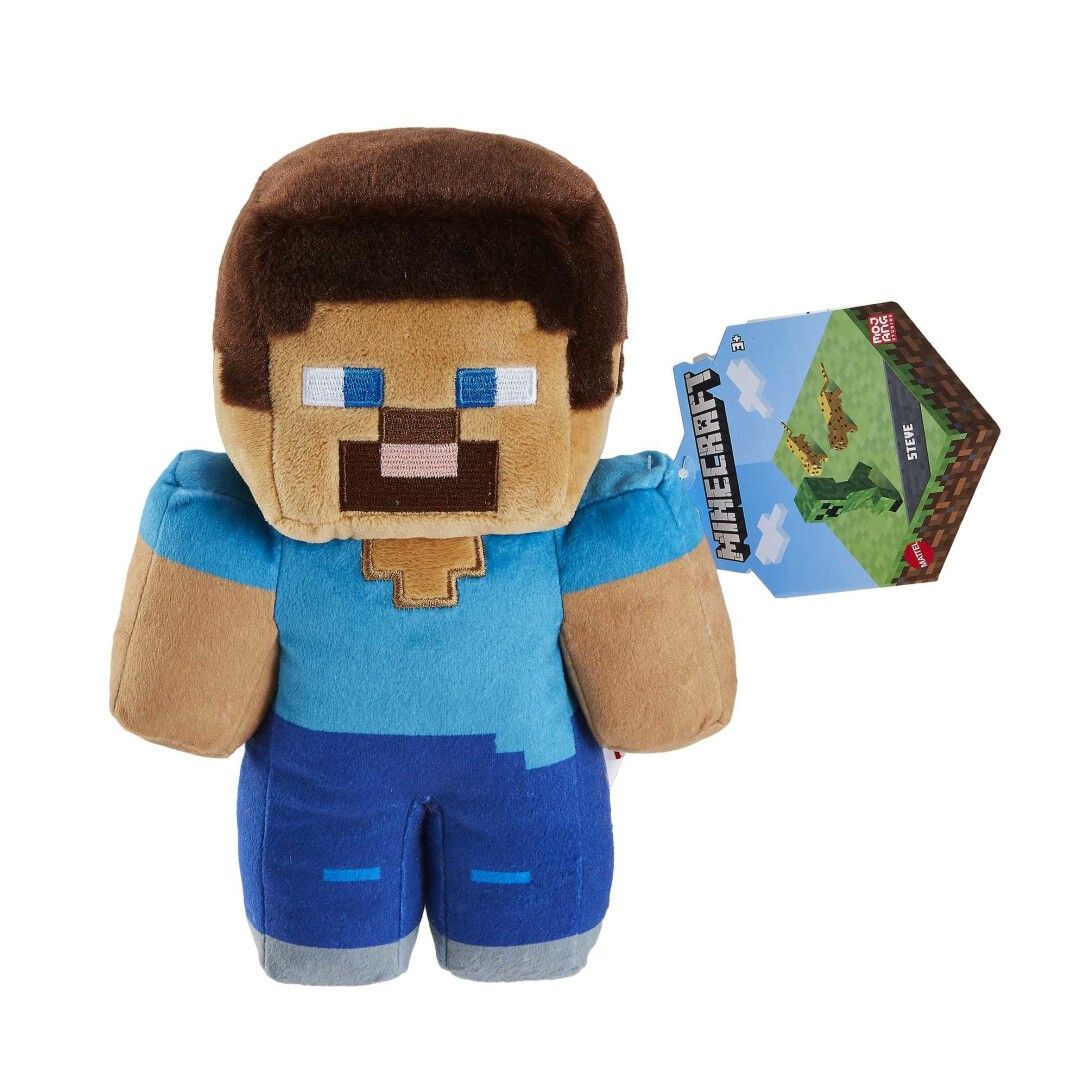 Peluche Steve, Minecraft. Beige, marrone, blu. Testa quadrata, occhi blu, barba marrone. Etichetta con logo.