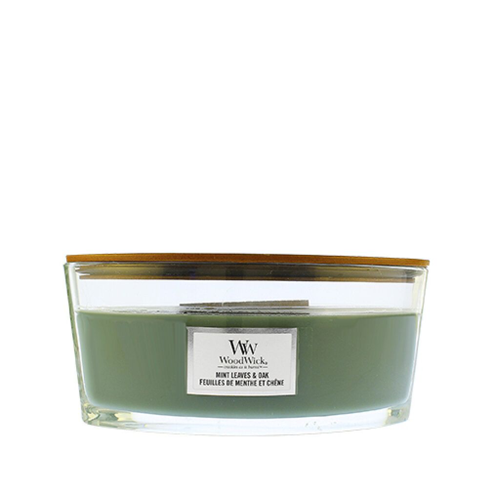 Candela ellittica con coperchio in legno. Cera verde in contenitore di vetro. Etichetta con nome del prodotto.