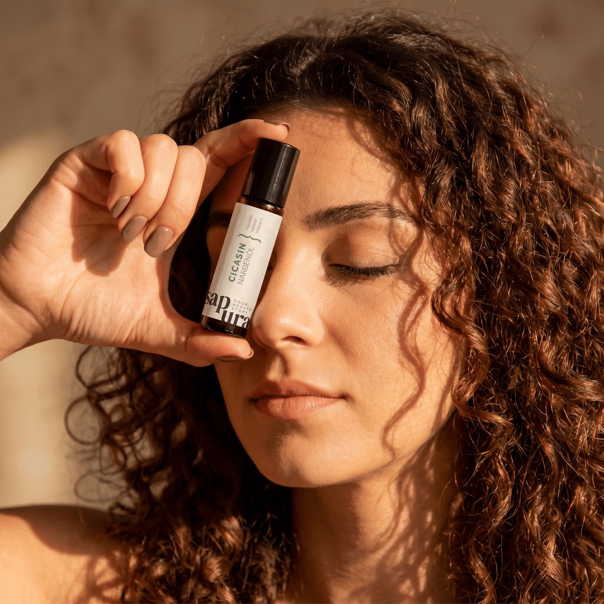 Una donna tiene un piccolo flacone di olio per cicatrici davanti al viso. L'etichetta è visibile.