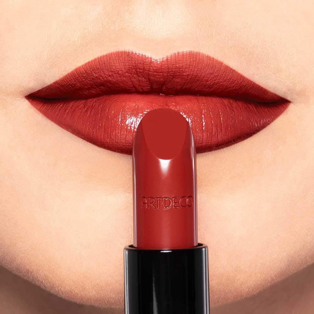 Rossetto rosso davanti alle labbra. Marchio Artdeco sul rossetto.