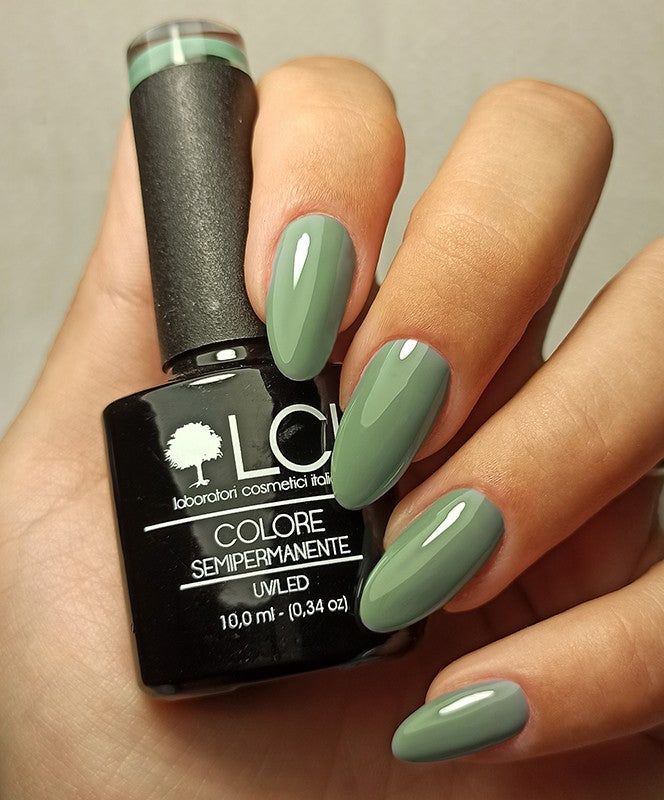Mano con unghie smaltate e flacone di smalto. LCI Cosmetics Smalto Semipermanente, colore Verde cadetto. Smalto verde.
