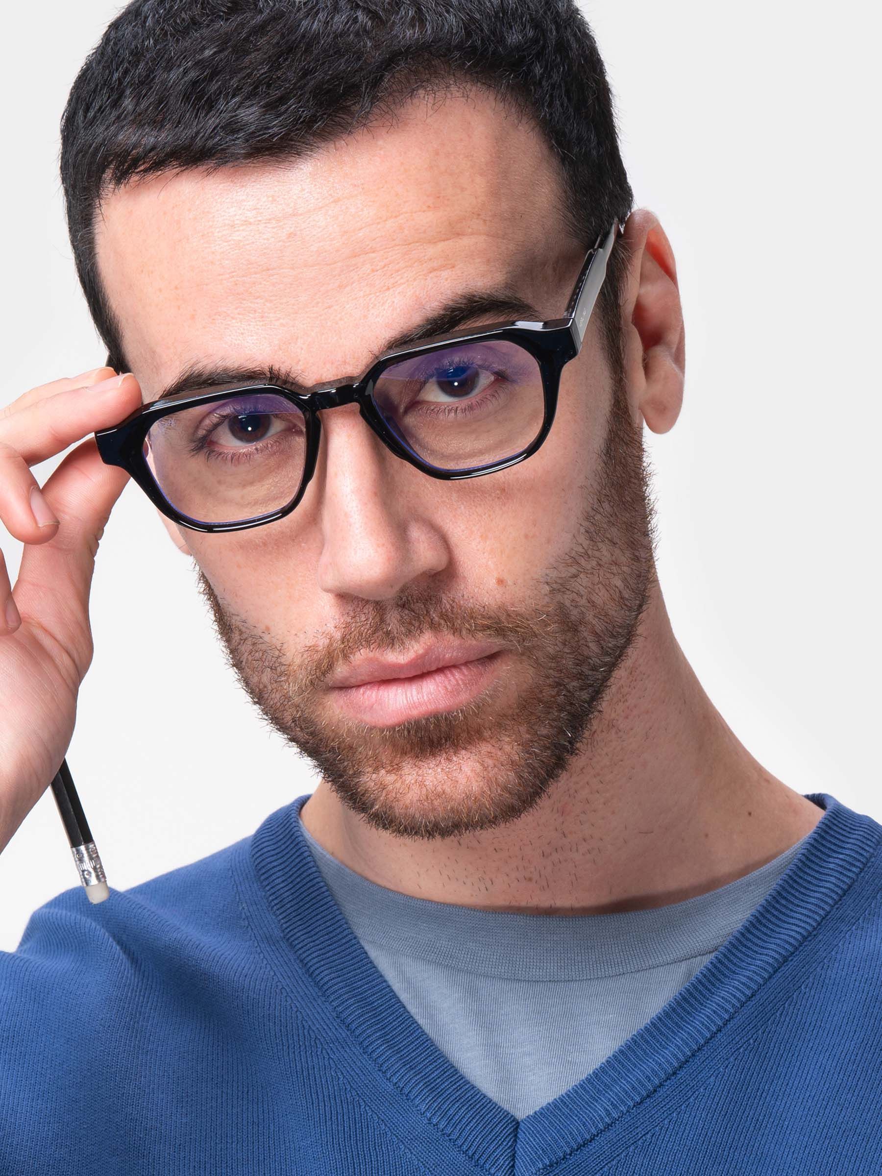 Uomo con occhiali neri. Montatura esagonale. Herling sull'asta. Maglione blu.