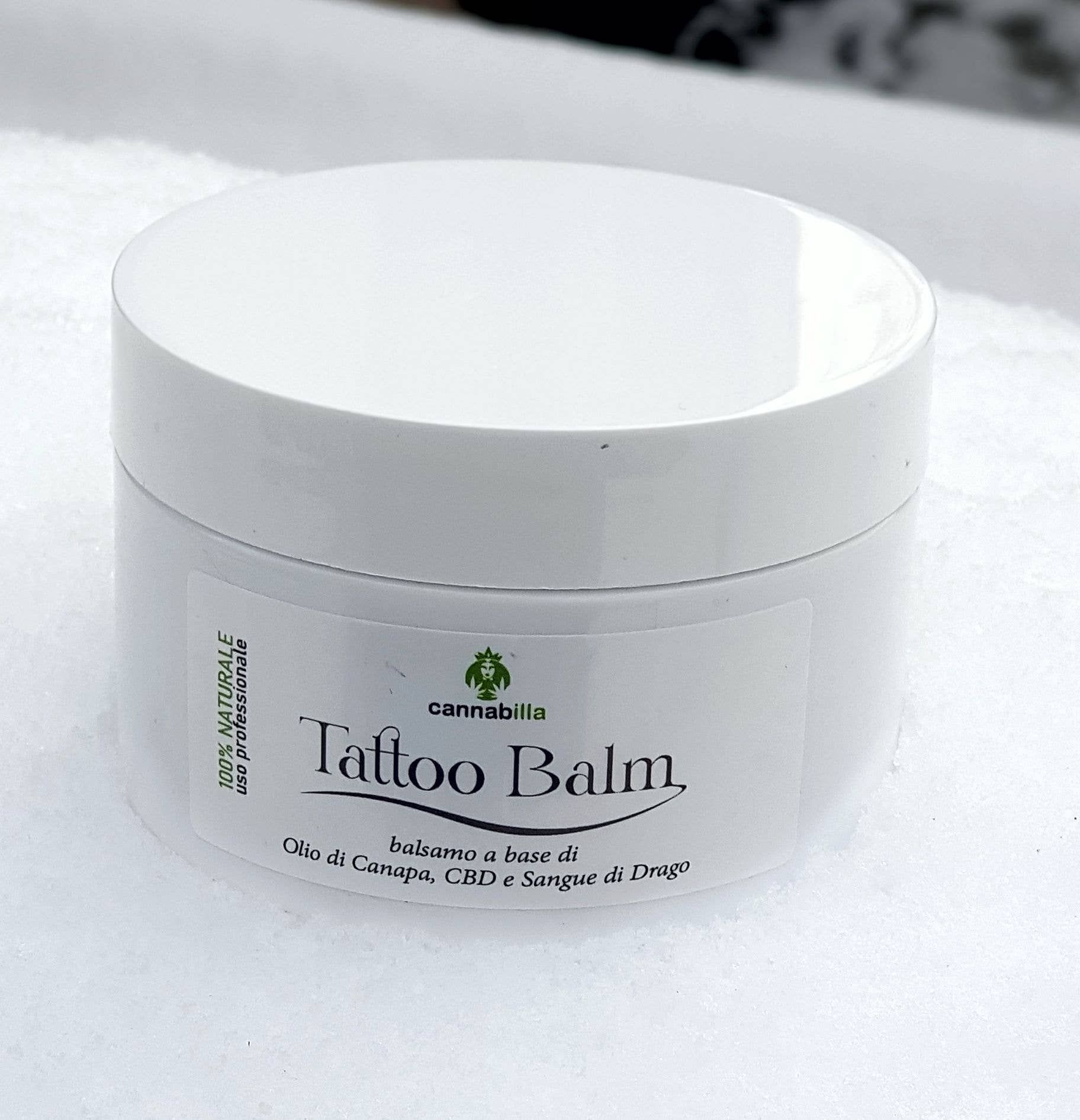 Vasetto bianco con scritta "Tattoo Balm". Scritta "balsamo a base di Olio di Canapa, CBD e Sangue di Drago".