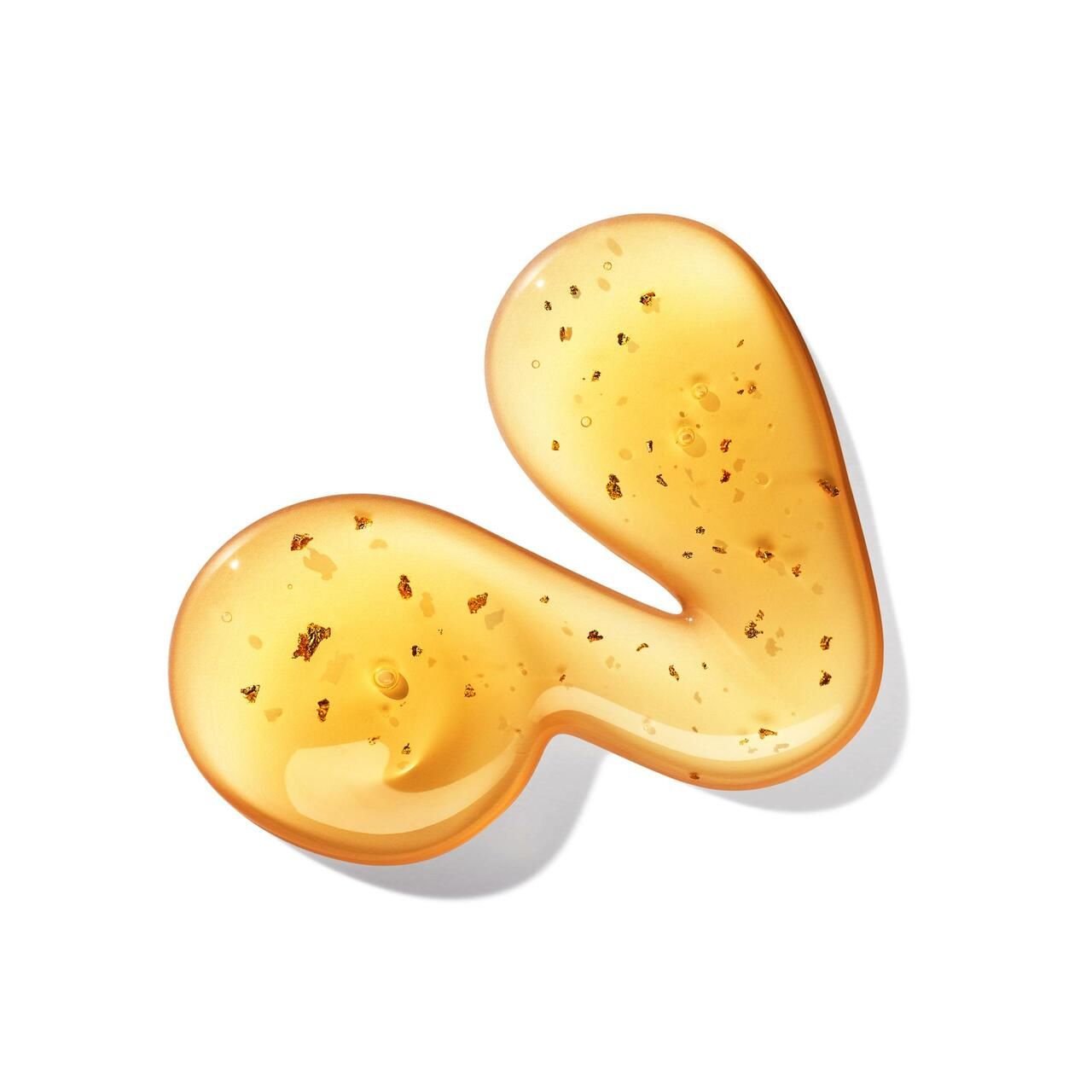 Goccia di gel dorata con piccole particelle dorate. Su sfondo bianco. Forma: irregolare, organica.