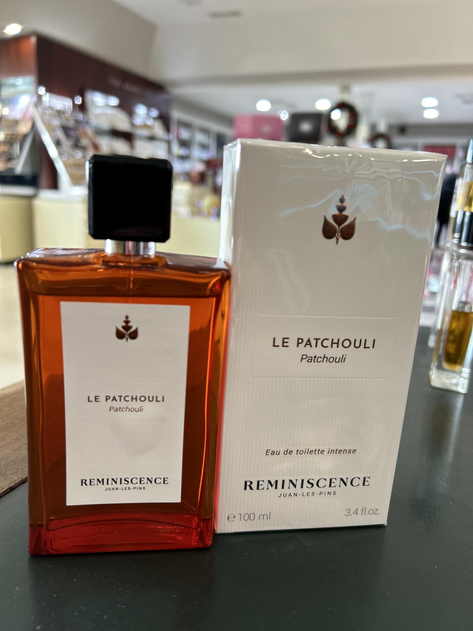 Flacone e confezione. Flacone rettangolare marrone con tappo nero. Confezione bianca con logo e testo.