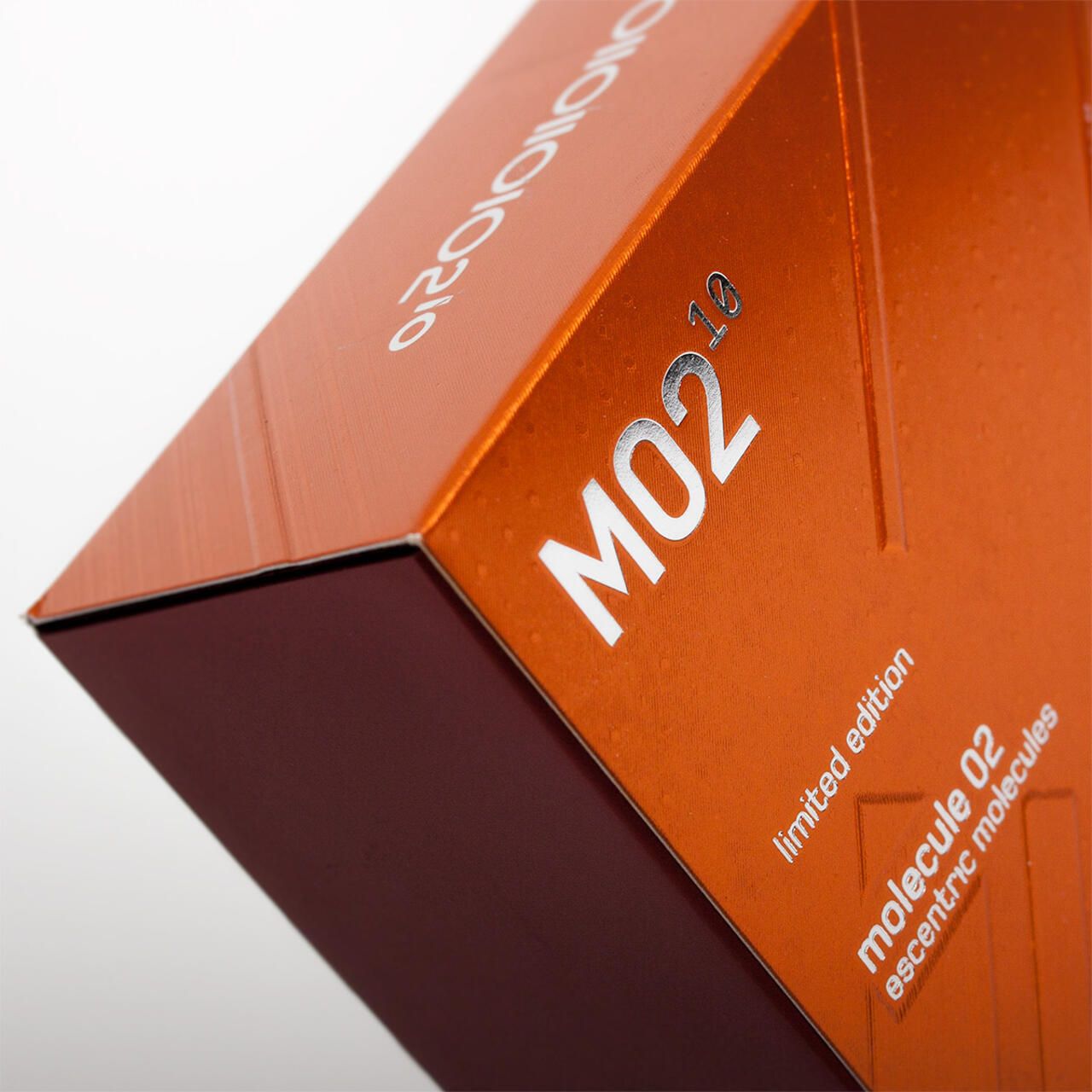 Scatola arancione con scritta argentata: MO2 10, limited edition, molecule 02, escentric molecules. Superficie lucida.