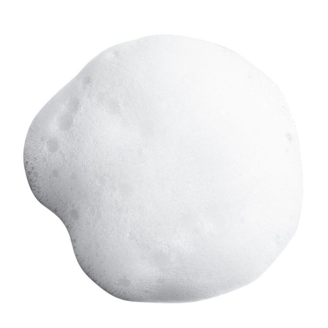 Cumulo di schiuma bianca. Forma rotonda con bordi irregolari. Bolle visibili.