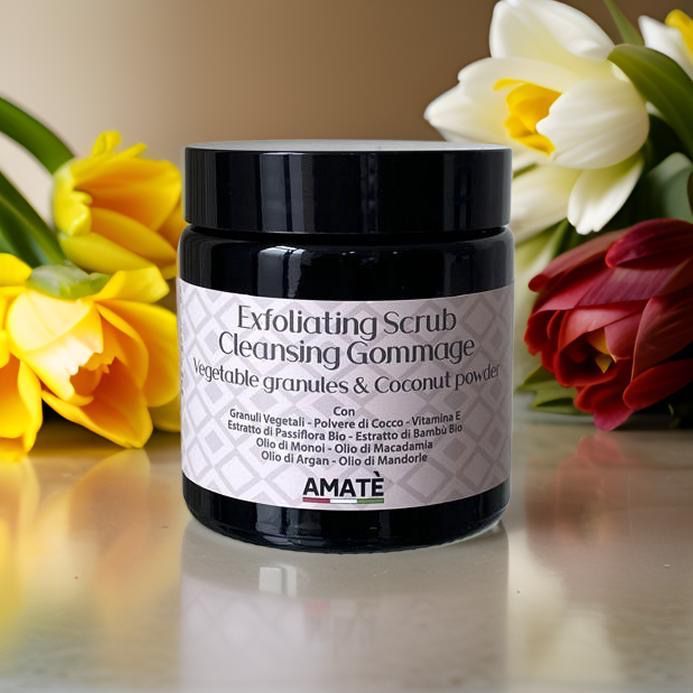 Barattolo scuro con etichetta, circondato da fiori. Testo: Exfoliating Scrub Cleansing Gommage, Vegetable granules & Coconut powder. Marchio: AMATÈ.