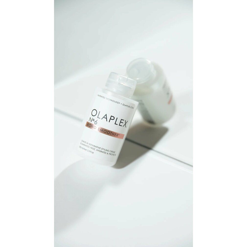 Due flaconi bianchi Olaplex No.6 Bond Smoother. Striscia marrone con testo. Su superficie bianca.